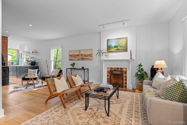 living area with a fireplace, light wood finished floors, rail lighting, and recessed lighting