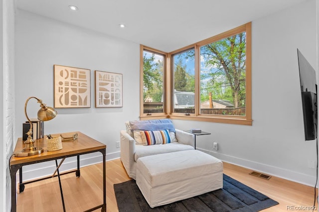 sitting room with healthy amount of natural light, wood finished floors, baseboards, and recessed lighting