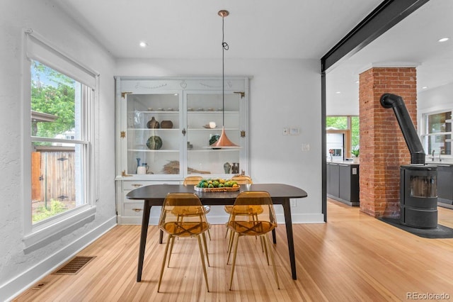 dining space with a wood stove, plenty of natural light, light wood-style flooring, and recessed lighting