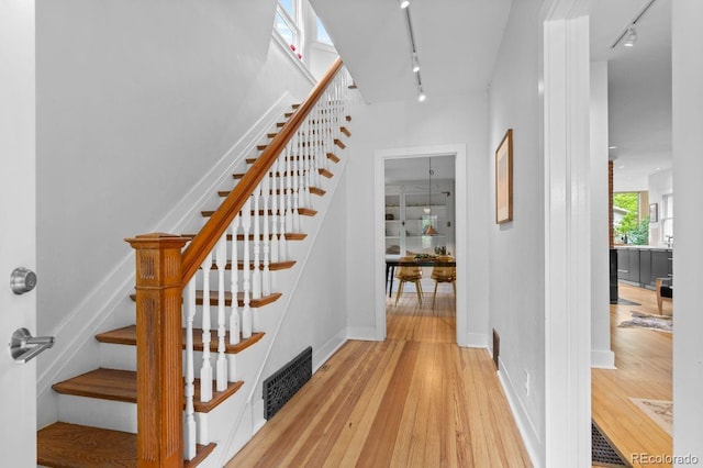 stairway featuring track lighting, hardwood / wood-style flooring, and baseboards