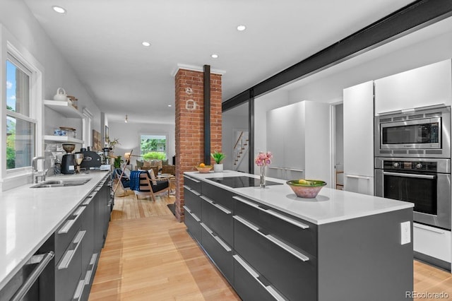 kitchen featuring appliances with stainless steel finishes, modern cabinets, a sink, light wood-type flooring, and recessed lighting