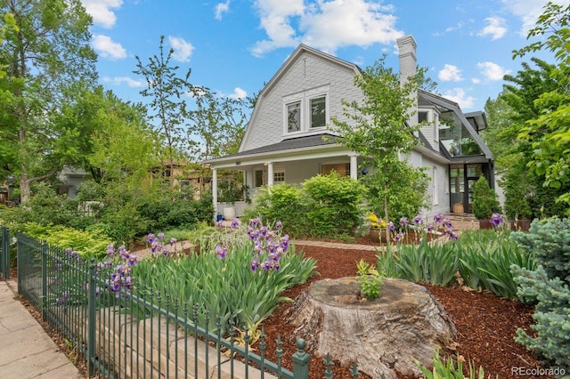 dutch colonial with a gambrel roof, fence, and a chimney