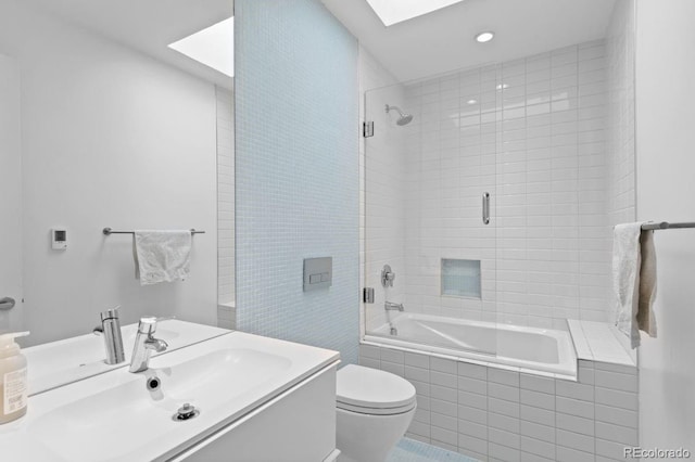 full bathroom with a skylight, tiled shower / bath, toilet, vanity, and recessed lighting