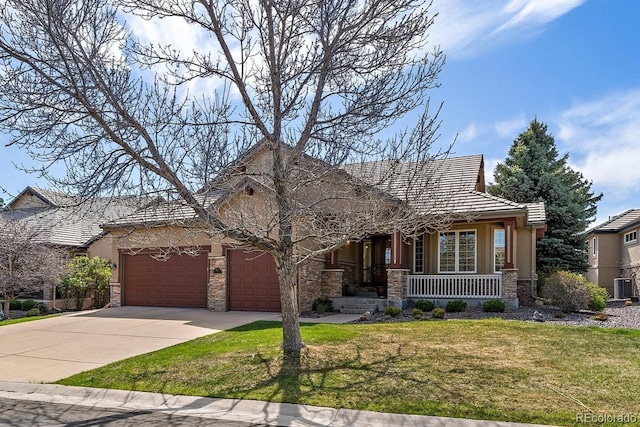traditional-style home featuring stone siding, a garage, a front yard, covered porch, and driveway