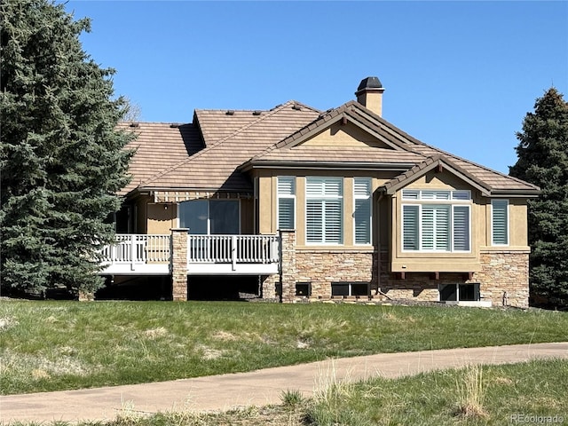 back of house with a lawn, a tiled roof, a chimney, and a wooden deck