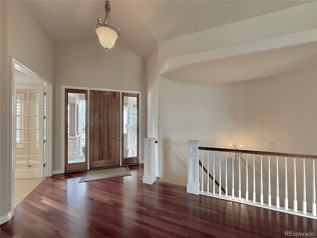 foyer entrance featuring baseboards, wood finished floors, and lofted ceiling