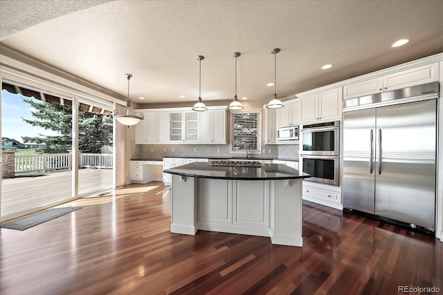 kitchen with a center island, white cabinets, stainless steel appliances, and dark wood-type flooring