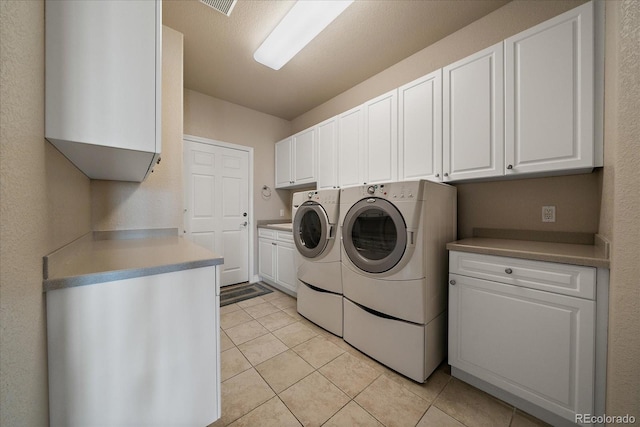 laundry room with light tile patterned floors, washing machine and dryer, and cabinet space