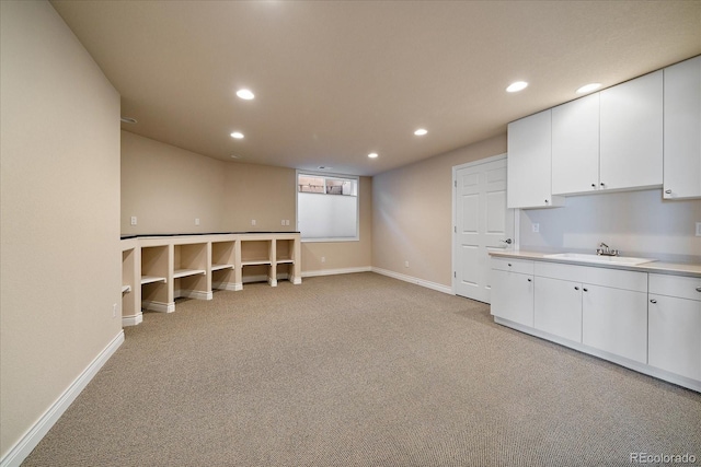 below grade area with a sink, baseboards, recessed lighting, and light colored carpet