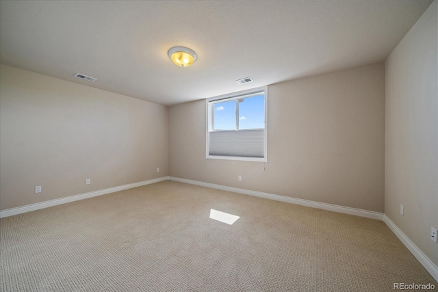 spare room featuring light colored carpet, baseboards, and visible vents