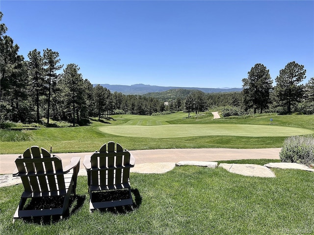 view of home's community with a yard, view of golf course, and a mountain view