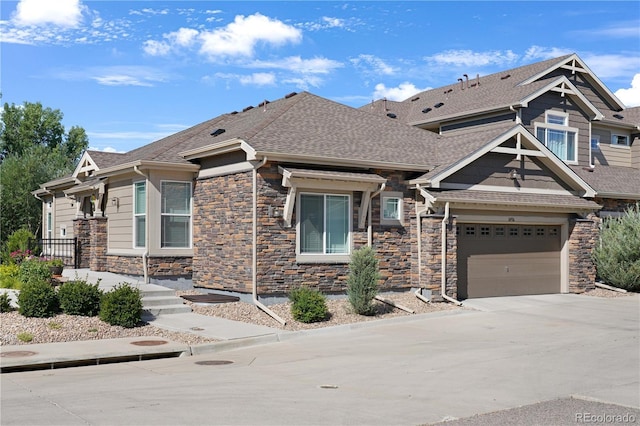 view of front facade featuring stone siding, roof with shingles, and concrete driveway