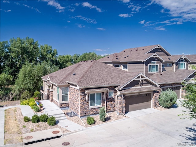 craftsman inspired home with concrete driveway, a shingled roof, an attached garage, and stone siding