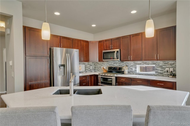 kitchen with a sink, stainless steel appliances, hanging light fixtures, and light countertops