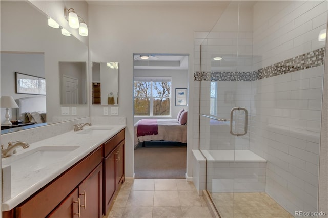 ensuite bathroom with ensuite bathroom, tile patterned floors, a sink, and a tile shower