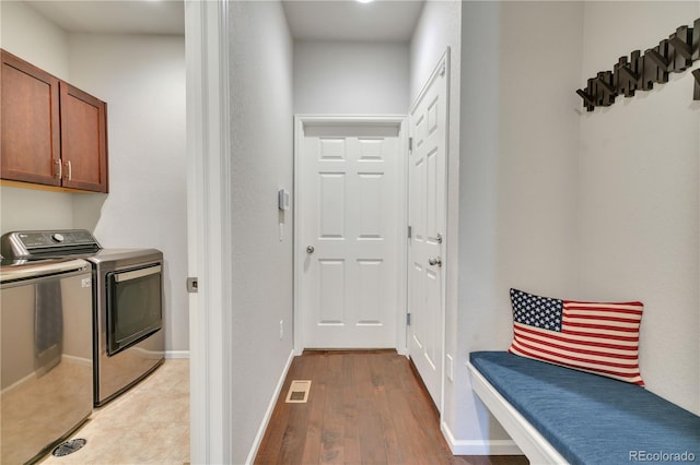 clothes washing area featuring cabinet space, baseboards, visible vents, washing machine and clothes dryer, and light wood-style floors