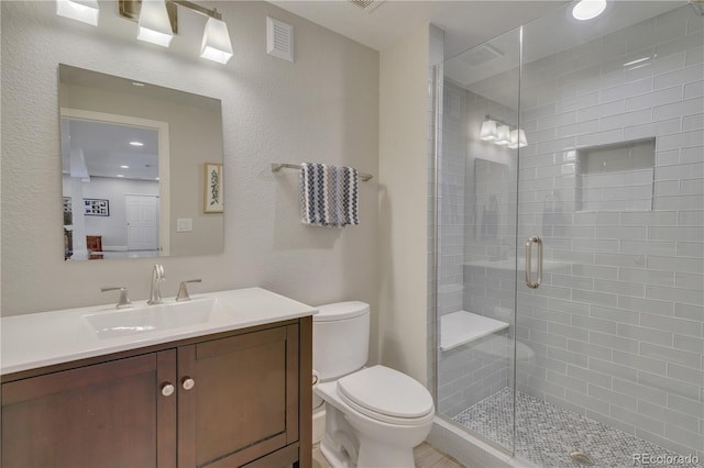 full bath featuring visible vents, vanity, a shower stall, and toilet