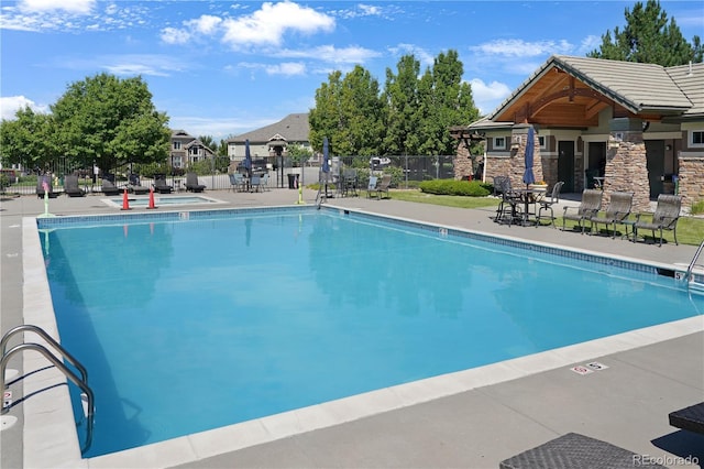 pool with a patio area and fence