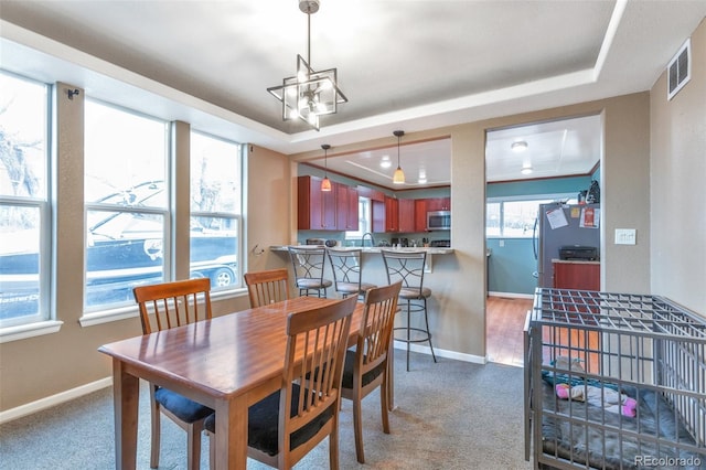 dining area with light colored carpet, a raised ceiling, and sink