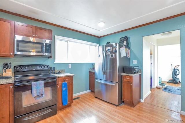 kitchen featuring light hardwood / wood-style flooring, light stone countertops, ornamental molding, and stainless steel appliances