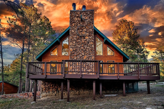 back house at dusk featuring a wooden deck