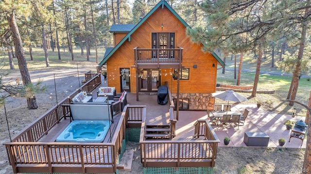 back of house with a patio, a balcony, a wooden deck, an outdoor hot tub, and an outdoor hangout area