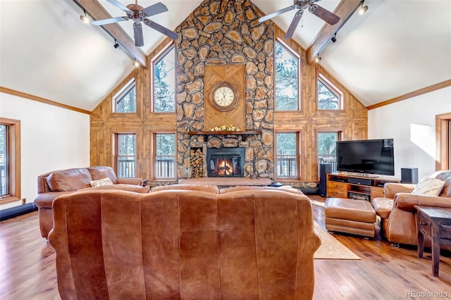 living room with ceiling fan, rail lighting, a stone fireplace, and light wood-type flooring