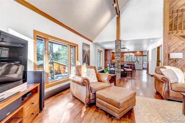 living room featuring crown molding, high vaulted ceiling, hardwood / wood-style flooring, ceiling fan, and decorative columns