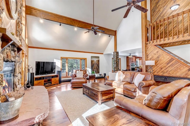 living room with ceiling fan, high vaulted ceiling, a high end fireplace, wood-type flooring, and wood walls