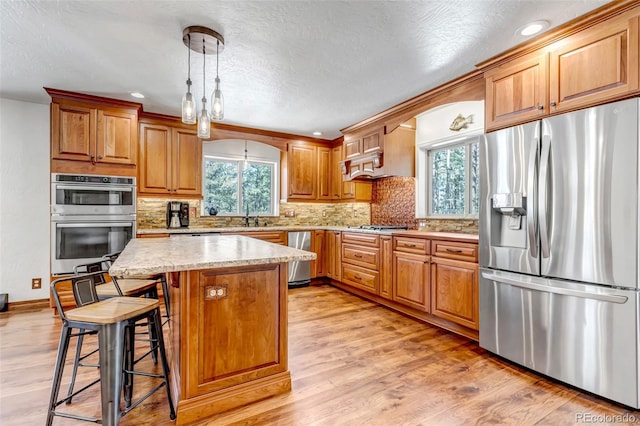 kitchen with a healthy amount of sunlight, appliances with stainless steel finishes, a center island, and pendant lighting