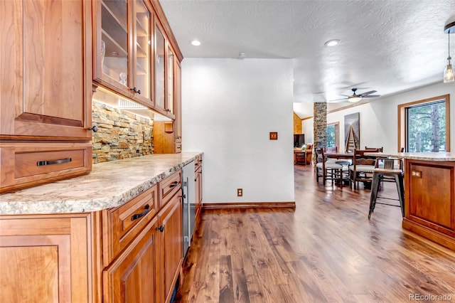 bar with ceiling fan, hardwood / wood-style floors, light stone counters, a textured ceiling, and decorative light fixtures