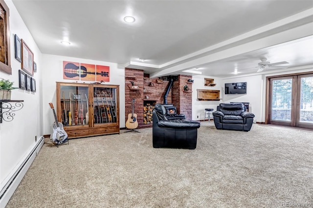 living room featuring a wood stove, baseboard heating, ceiling fan, brick wall, and carpet