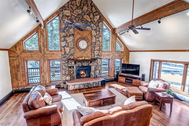 living room featuring a fireplace, light hardwood / wood-style flooring, beamed ceiling, and ceiling fan