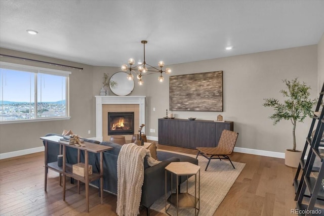 1721 Wingfeather Ln, Castle Rock, CO 80108 - living room featuring wood finished floors, a tiled fireplace, a chandelier, and recessed lighting
