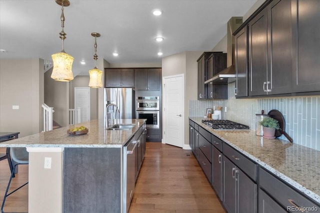 1721 Wingfeather Ln, Castle Rock, CO 80108 - kitchen featuring wall chimney range hood, appliances with stainless steel finishes, dark wood-style floors, a breakfast bar, and backsplash