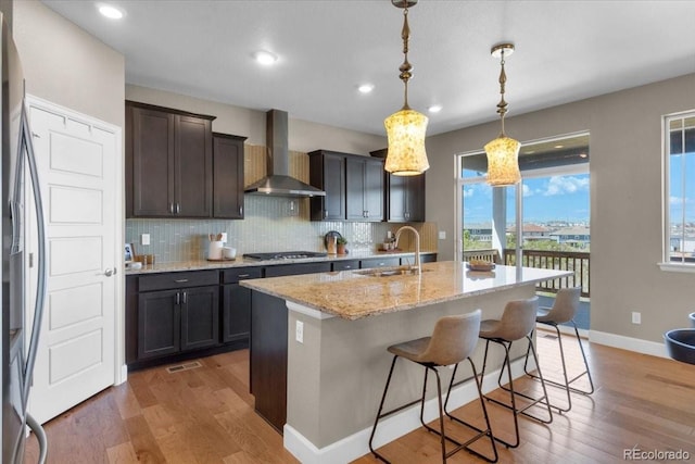 1721 Wingfeather Ln, Castle Rock, CO 80108 - kitchen with wall chimney range hood, fridge, stainless steel gas stovetop, backsplash, and light stone counters