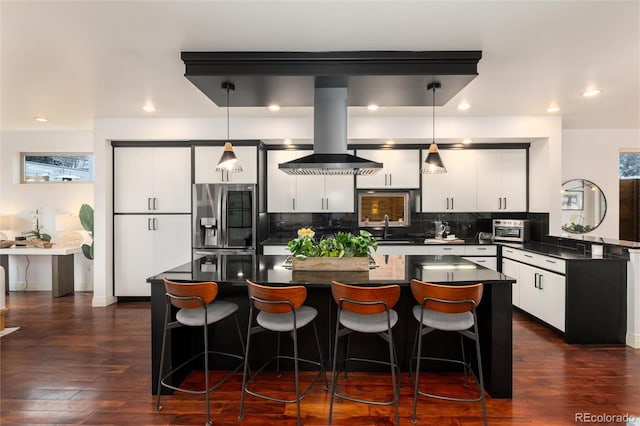 kitchen with a center island, hanging light fixtures, dark hardwood / wood-style flooring, stainless steel fridge, and white cabinets