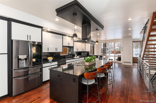 kitchen featuring a center island, stainless steel fridge with ice dispenser, island exhaust hood, decorative light fixtures, and white cabinets