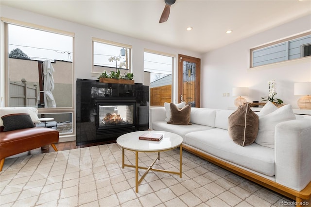 living room with ceiling fan, light hardwood / wood-style floors, and a multi sided fireplace