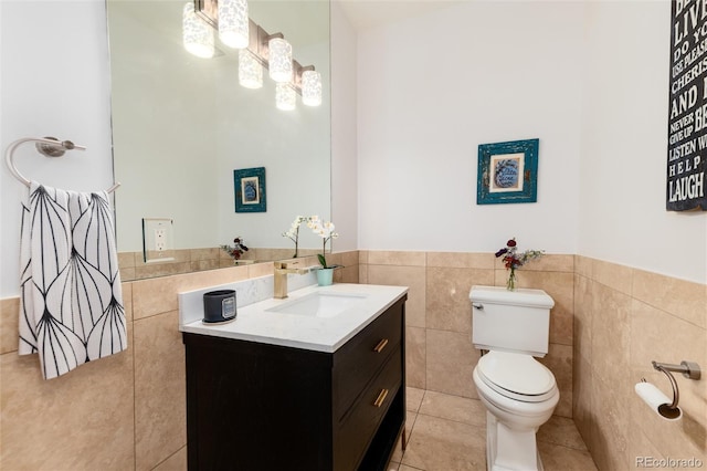 bathroom featuring tile patterned flooring, vanity, toilet, and tile walls