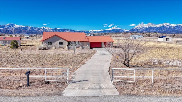 ranch-style house featuring a garage, a mountain view, and a rural view