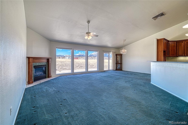 unfurnished living room featuring dark carpet, ceiling fan with notable chandelier, vaulted ceiling, and a textured ceiling