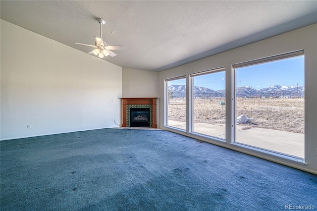 unfurnished living room with vaulted ceiling, a mountain view, carpet flooring, and a fireplace