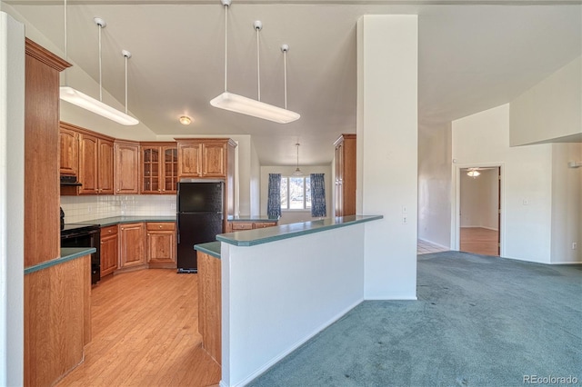 kitchen with pendant lighting, lofted ceiling, black appliances, decorative backsplash, and kitchen peninsula