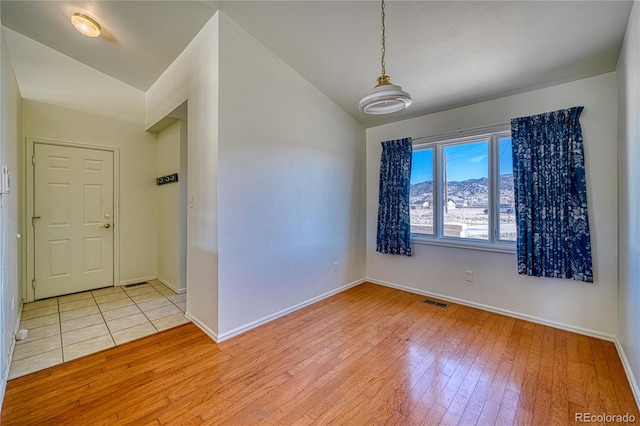 unfurnished room with lofted ceiling and light wood-type flooring