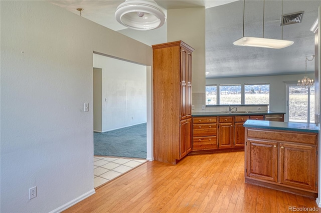 kitchen featuring sink, hanging light fixtures, a notable chandelier, light hardwood / wood-style floors, and a textured ceiling