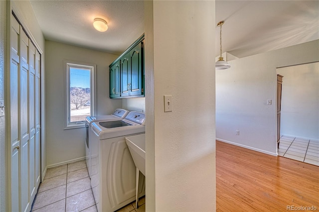 laundry room with cabinets, washer and clothes dryer, a textured ceiling, and light tile patterned floors