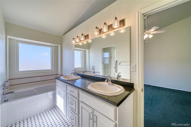 bathroom featuring a relaxing tiled tub, vanity, and ceiling fan