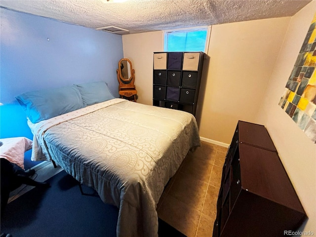 bedroom featuring dark tile patterned flooring and a textured ceiling