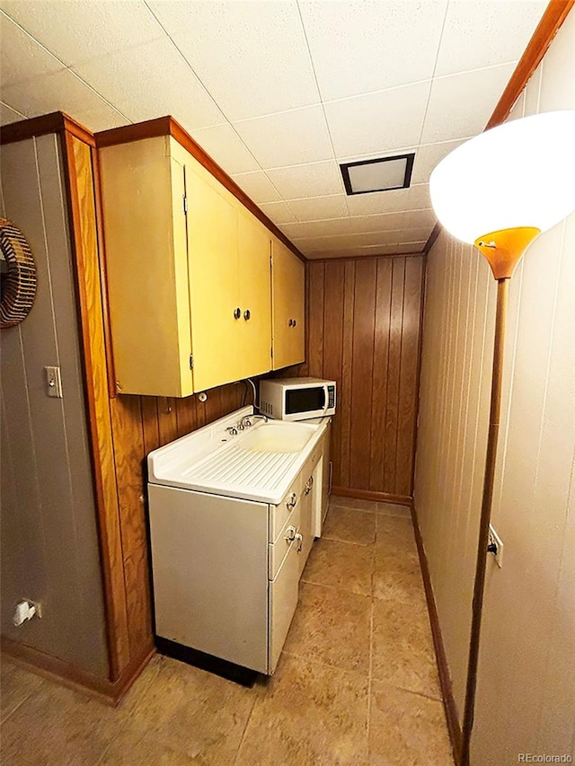 washroom with washer / clothes dryer, wooden walls, and cabinets